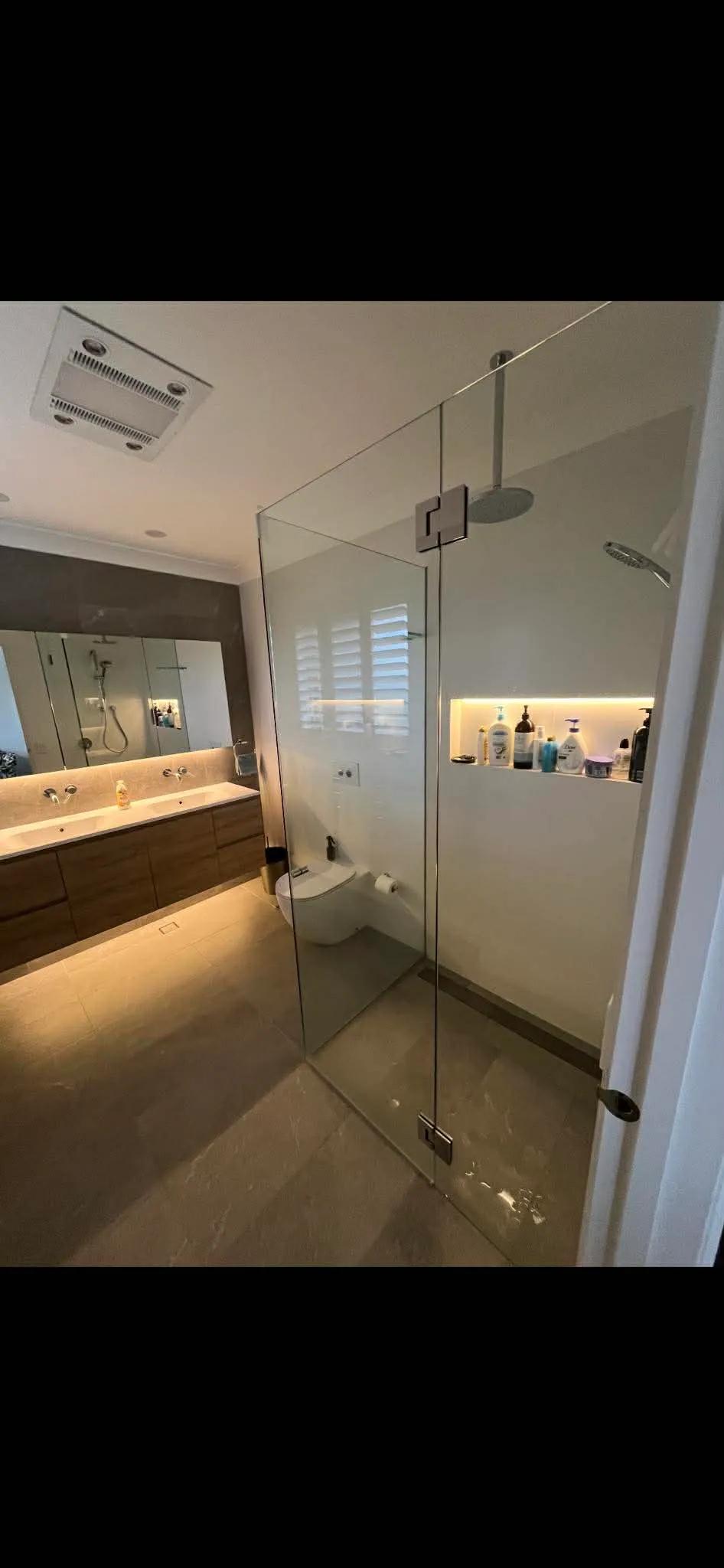 Modern bathroom with frameless glass shower, niche and floating timber vanity