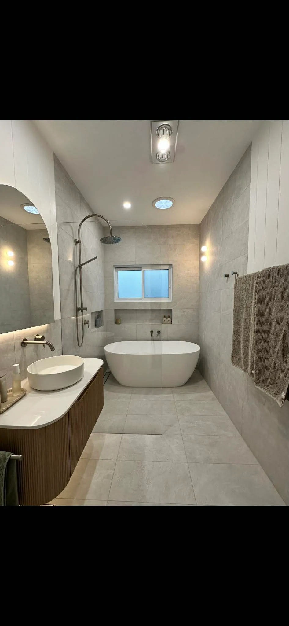 Full bathroom renovation with freestanding tub and fluted timber vanity