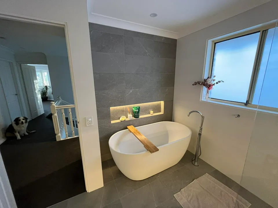 Bathroom renovation with freestanding tub, charcoal feature tile and lit niche
