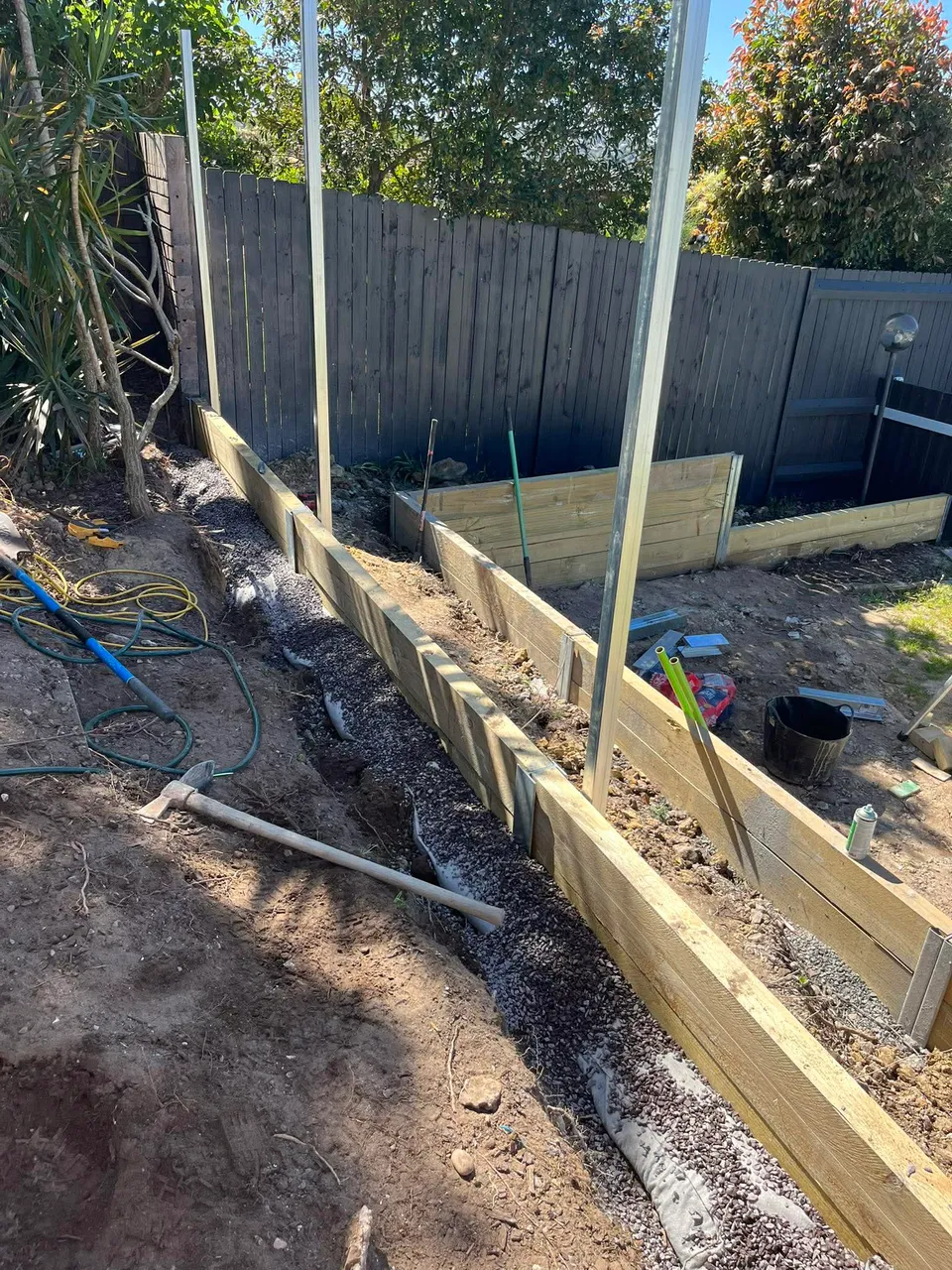 Treated pine retaining wall and drainage along boundary fence line