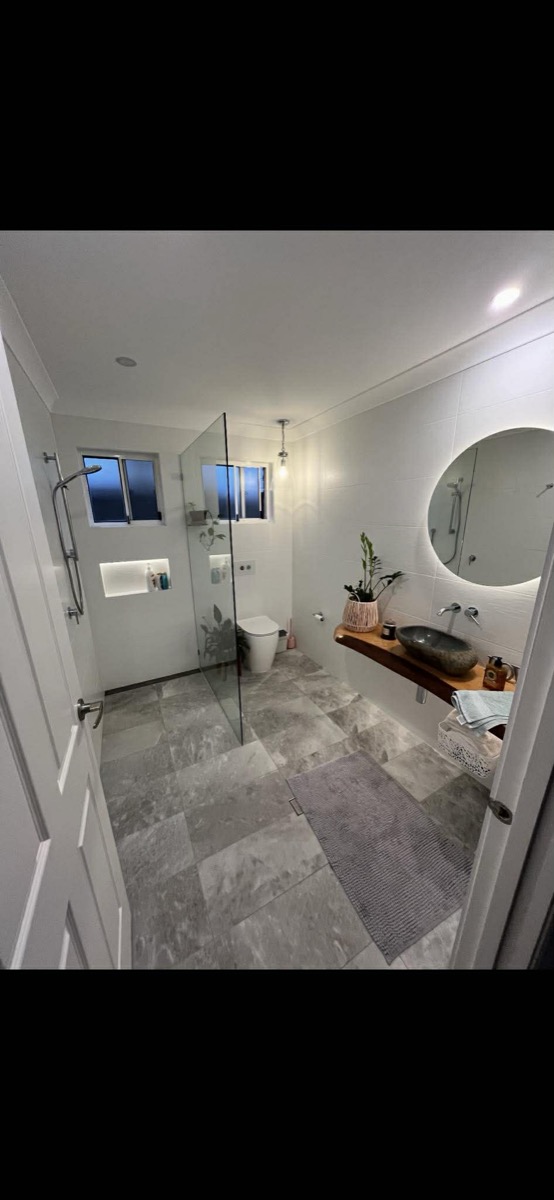 Bathroom with stone basin, round LED mirror and timber shelf