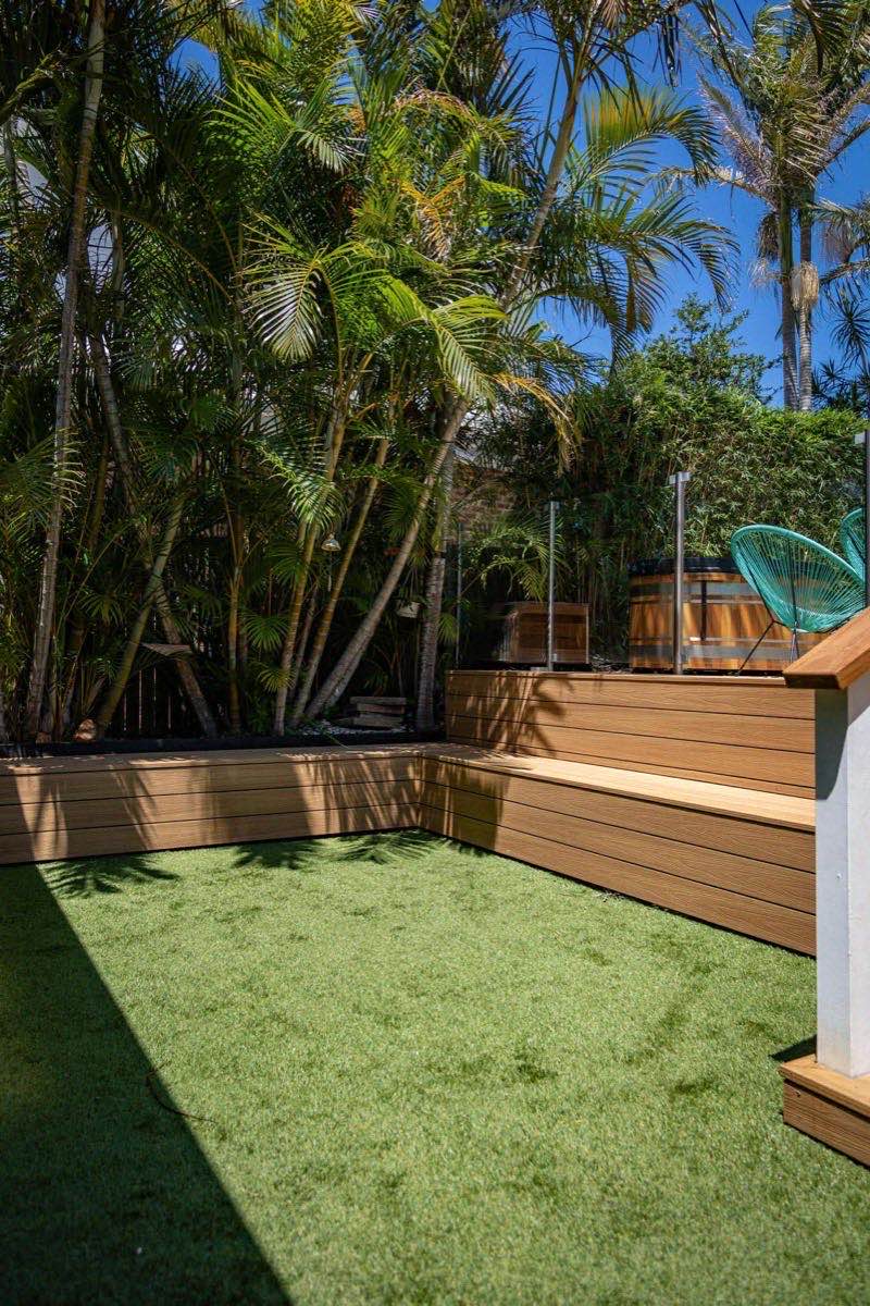 Composite deck with tropical landscaping and glass pool fence